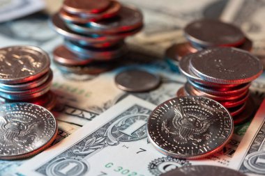 Amerikan doları banknotlarında dolar sikkeleri. Refah için birikmiş madeni paralar. Önünde yarım dolar var..