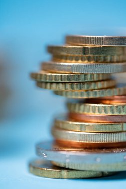 Euro sikkeleri bir kuleye yığıldı, Avro para birimine yakın. Bozuk para kulesinin arkasında mavi arkaplan