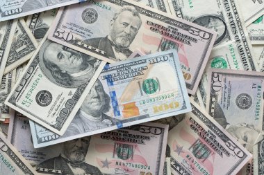 Dolarlar etrafa saçıldı. Bir ila yüz dolarlık banknotlar. Amerikan doları banknotlarıyla dolu bir geçmişi var. Nakit 100 ve 50 dolar.