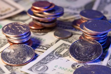 Dolar banknotlarının üstüne yığılmış bir sürü bozuk para. Bozukluklardan yarım dolara yükselen bozuk paralar