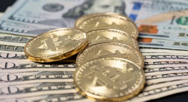 50 ve 100 dolarlık banknotların üzerine bitcoin yığılmış. Dijital para ticaretinden Amerikan dolarına. Kripto ticaret ve takas kavramı