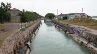 Rosignano, İtalya - 8 Haziran. 2021: Kimya Tesisi 'ne giden kanal, Deniz suyu kanalı. Duvarların kenarlarında grafiti