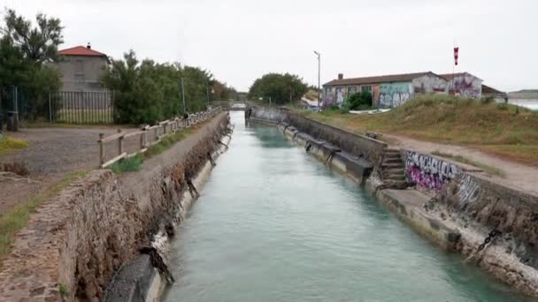 イタリア ロジニャーノ 6月8日 2021 化学プラント 海の水チャンネルにつながる運河 壁の両側に落書き — ストック動画