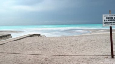 Banyo yapmayı, ayakta durmayı ya da aylak aylak dolaşmayı yasaklayın. Kirli su yasak bölge. Arka planda turkuaz su ve beyaz kum