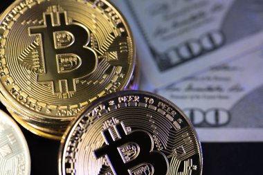 Arka planda ABD Doları banknotları olan Bitcoin paraları