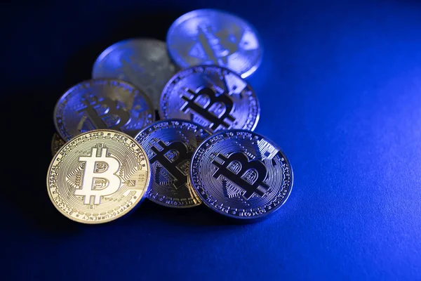 Bitcoin paralar maviyi aydınlatır. Engelleme teknolojisi konsepti. Dijital para ticareti. Karanlıkta bozuk paralarla çevrili bir Bitcoin.