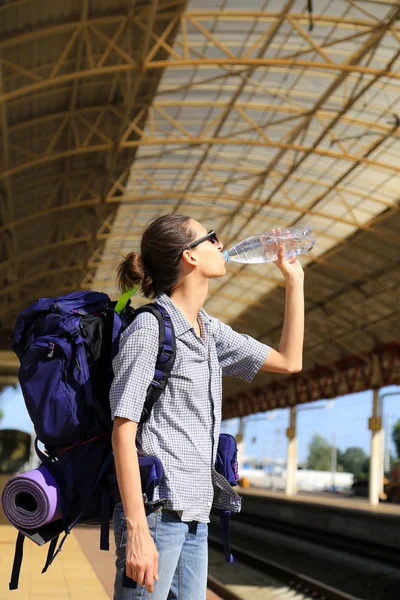 Backpackers meisje te wachten voor de trein, meisje water drinkt — Stockfoto