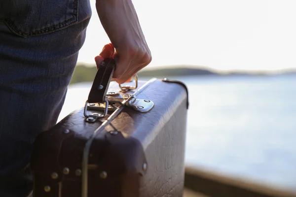 Bagage i en kvinnlig hand på en bakgrund av havet — Stockfoto