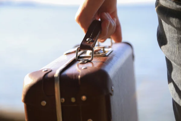 Luggage in a female hand on a background of the sea — Stock Photo, Image