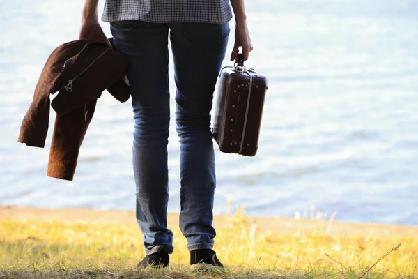 Bagage in een vrouwelijke hand op een achtergrond van de zee — Stockfoto