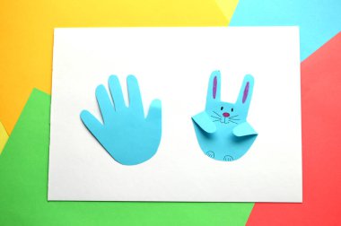 Paskalya el sanatları. Avucunun içindeki çocuk izinden renkli kağıt tavşanlar.