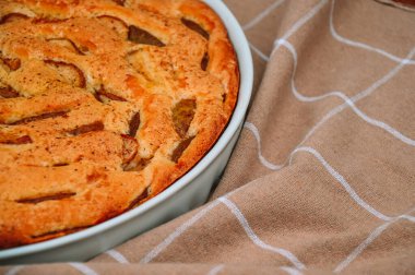 Charlotte 'un elmalı turtası bej bir mutfak havlusunun arka planında beyaz seramik formda. Taze kokulu hamur işleri. Evde rahat bir sonbahar.