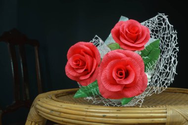 Güzel bir çiçek buketi (kağıt kırmızı gül) bir çiftin aşkı için eski bir masanın üzerinde