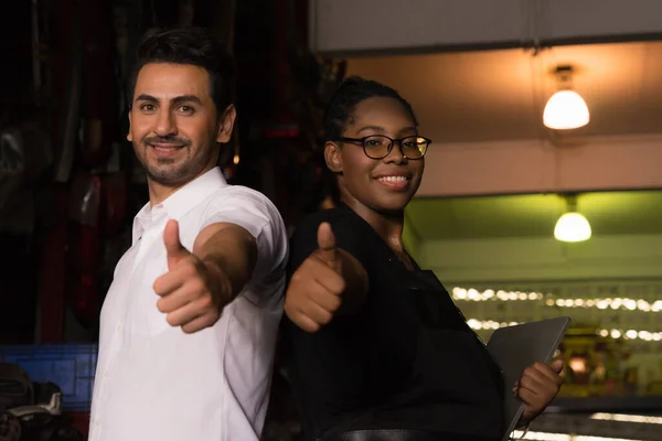 Man work with woman, they happy and give thumbs up. Diversity of two people, caucasian business manager and African worker woman happiness and give thumbs up in factory-warehouse