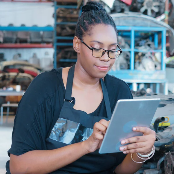 Black African worker woman sitting, using tablet in factory-warehouse