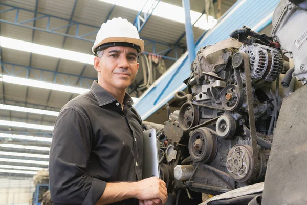Mühendis çalışıyor, Kafkasyalı yönetici kaskı fabrika deposundaki motora bakıyor.