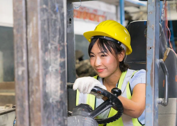 Fabrika deposunda forklift kullanırken sol tarafa bakan sevimli Asyalı mühendis kadınlar.