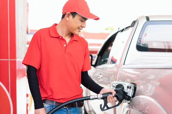 Asian gas station worker man filling high energy power fuel in auto car tank in petrol station, commercial service for benzine, diesel, gasohol, gasoline.