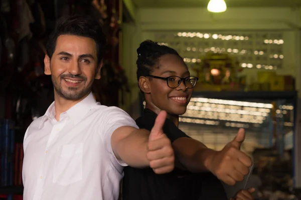 Man work with woman, they give thumbs up to team. Diversity of two people, caucasian business manager and African worker woman give thumbs up to team in factory-warehouse