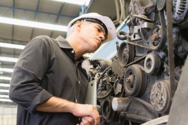 Mühendis çalışıyor, Kafkasyalı yönetici fabrika deposunda kullanılan motoru inceliyor.