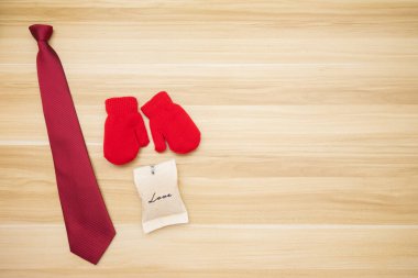 Çocuk sahnesini markasız eldivenle temsil etmek, babaya ahşap arka planlı kırmızı kravat ve aşk çantası hediye eder. Çocuk arka planında Babalar Günü konseptinde babaya mutlu bir hediye veriliyor.