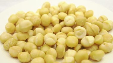 Macadamia fındıklarının tabağa düşüşünün yavaş çekim sahnesi, meze olarak macadamia fındıklarını yakın çekim.