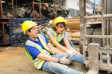 Orta ölçekte çalışan bir adamın kaza geçirmesi, makinistin bacağının üzerinde forklift. Asyalı mühendis bir forklift ve bir mühendis tarafından ezildi ve fabrika deposu atışında ona yardım eden mühendis kadın makinistin bacağını kaldırdı. Asyalı mühendis ezildi. 