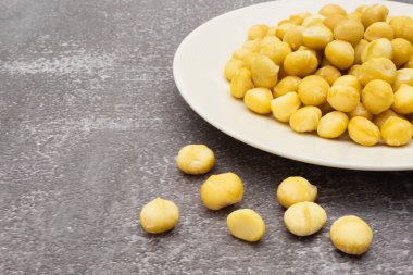 Taş zeminde çiğ macadamia tohumları, sağ tarafta Macadamia fındıkları ve çerçevenin sol tarafında uzayı kopyalamak.