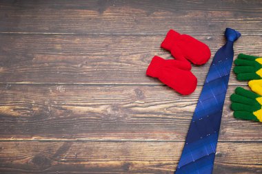 Çocuk ve oğlunun markasız eldivenlerle temsil edildiği sahne koyu renk ahşap arka planlı babaya mavi kravat hediye ediyor. Çocuk arka planında Babalar Günü konseptinde babaya mutlu bir hediye veriliyor.