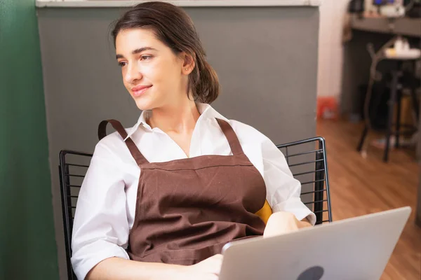 Kafkasyalı güzel kadın kahve dükkanının önünde boş boş otururken dinleniyor ve mola zamanında dizüstü bilgisayar kullanıyor. Kahve barında ve yemek servisinde çalışıyor.