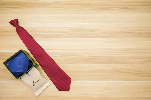 Scene of blue tie in box, red tie, and love bag for dad at left side with wood background. Background scene of child gives happy gift to father in father\'s day concept