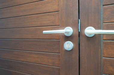 Kapalı paslanmaz kapı tokmağı ya da güvenlik anahtarıyla gerçek kahverengi ahşap kapı ön kapısına kilitlenip evin dış cephesinde klasik stile sahip..