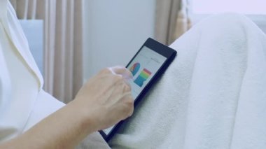 Asyalı iş adamı evde tablet üzerinde mali tabloyla ya da grafikle çalışır, işçi oturur ve evde veri analizi için grafikler ya da grafikler üzerinde çalışır