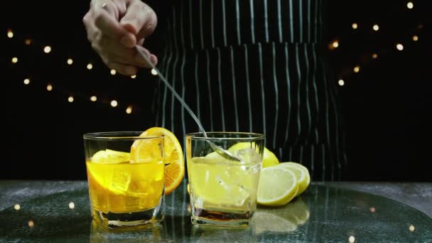 男はテーブルの上にオレンジジュースの横に新鮮なレモングラスで氷を攪拌 バーテンダーはバーでパーティーで飲むためのフルーツカクテルや新鮮なジュースを準備します — ストック動画