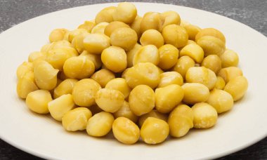 Çerçevenin ortasında çiğ macadamia tohumları tabakların üzerinde taş arka planda, macadamia fındıklarını kapatın.