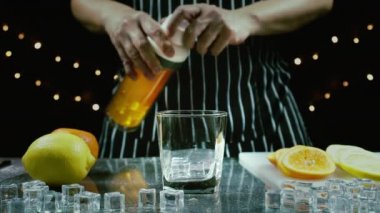 Barmen bardağa limon suyu döker masaya taze limon ve portakal koyar, barmen meyve kokteyli ya da barda içmek için taze meyve suyu hazırlar.