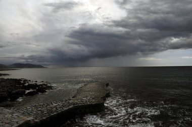 Gerolimenas, Mani, Moreloponnese, Yunanistan 'daki küçük taşlı iskele, gri, yağmurlu ve tehditkar kış gökyüzünün altında