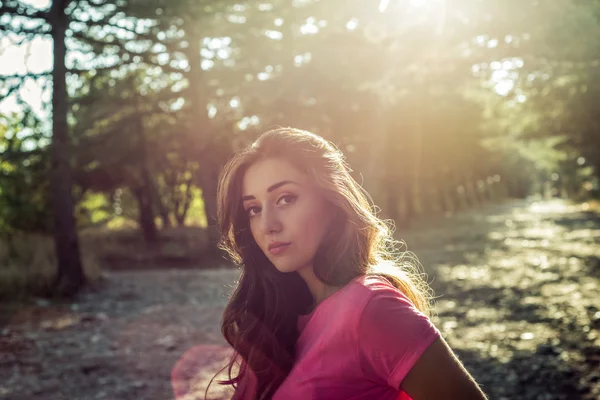 Retrato de bela jovem mulher em contra o fundo do sol — Fotografia de Stock