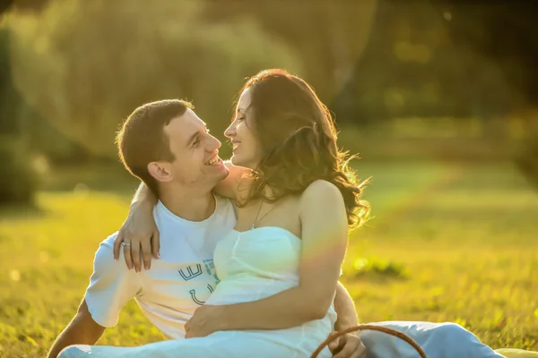 Feliz casal grávida sentado na grama no parque — Fotografia de Stock