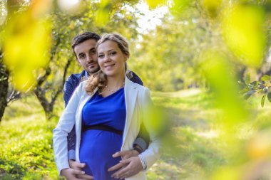 Sarı yapraklar parkta oturan genç hamile Çift