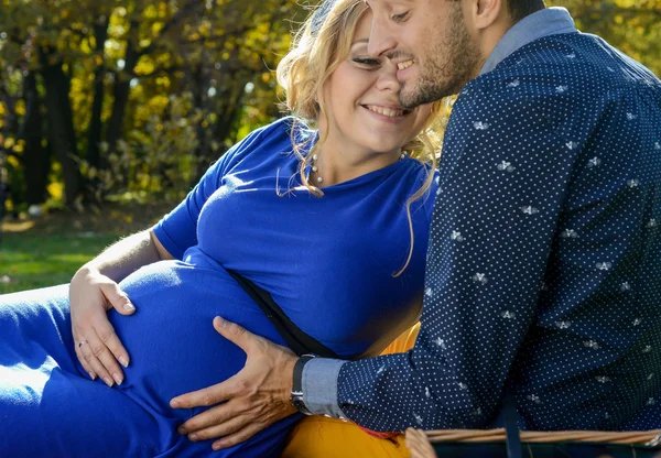 Pais felizes esperando bebê, tocando barriga, sentado na grama verde — Fotografia de Stock