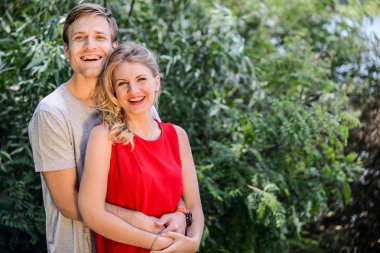 Genç mutlu çifte sarılma ve yaz parkta gülüyor