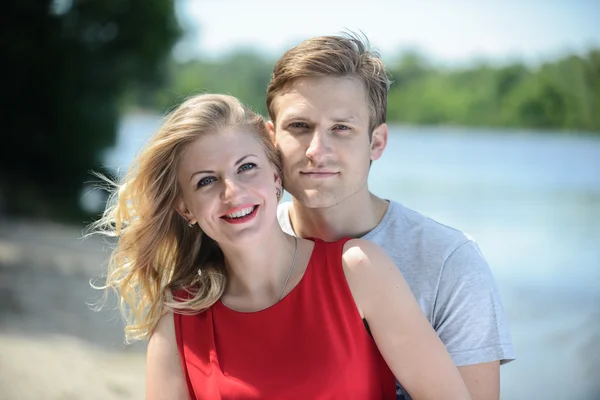 Giovane coppia felice abbracciare e ridere sullo sfondo del fiume — Foto Stock