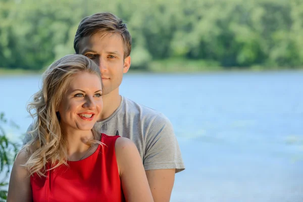 Jonge gelukkige paar knuffelen en lachen op rivier achtergrond — Stockfoto