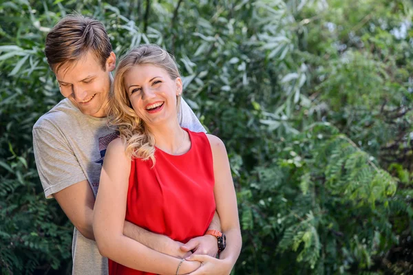 Jovem casal feliz abraçando e rindo no parque de verão — Fotografia de Stock