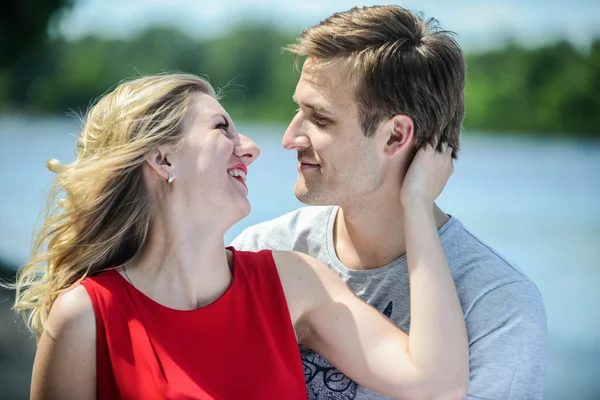 Giovane coppia felice abbracciare e ridere sullo sfondo del fiume — Foto Stock