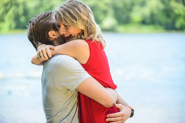 Молодая счастливая пара обнимается и смеется на фоне реки — стоковое фото