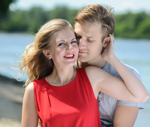 Jonge gelukkige paar knuffelen en lachen op rivier achtergrond — Stockfoto