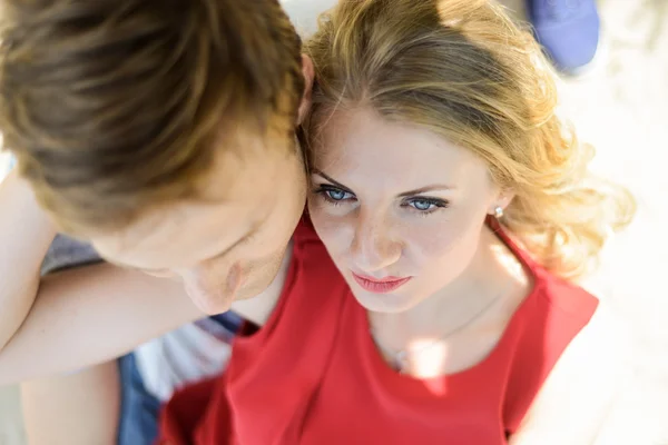 Young couple sitting on the sand smiling and hugging — Stock Photo, Image