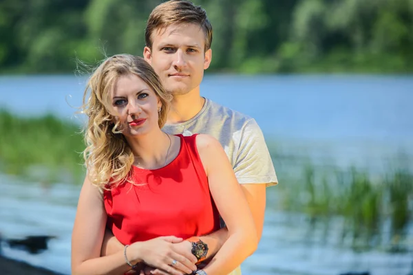 Jonge gelukkige paar knuffelen en lachen op rivier achtergrond — Stockfoto